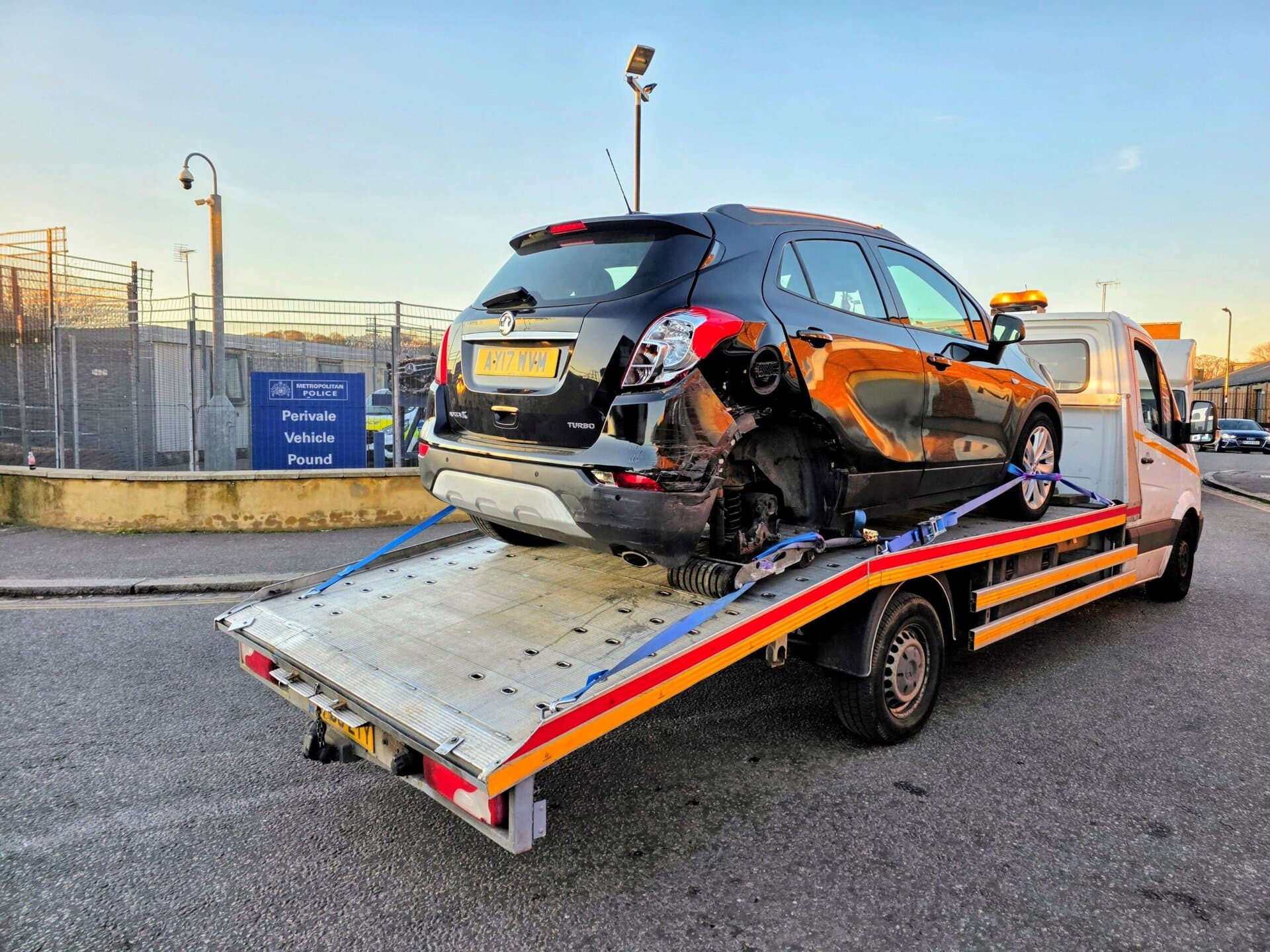 Black Vauxhall Mokka loaded on a flatbed recovery truck outside Perivale Vehicle Pound for professional police compound car recovery London service.
