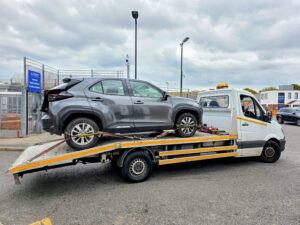 Professional recovery of a grey Toyota Yaris Cross from a Metropolitan Police vehicle pound onto a flatbed tow truck.