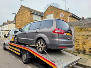 Grey Ford Galaxy loaded on a flatbed recovery truck for professional scrap car collection Kingston.