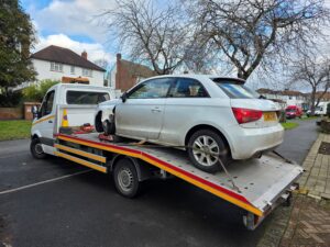 White Audi A1 with front damage being recovered with skates after an accident on a residential road in Fulham SW6.