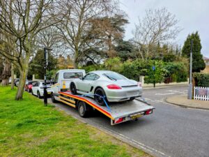 Silver Porsche Cayman on a flatbed recovery truck for breakdown recovery Fulham service in a local SW6 residential street.