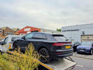 Professional emergency car recovery Wimbledon showing a black Audi Q8 delivered to the Audi dealership on a reliable flatbed recovery truck in SW19.
