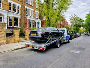 Black Tesla Model S on a flatbed recovery truck for electric car recovery Fulham service in a residential SW6 street.