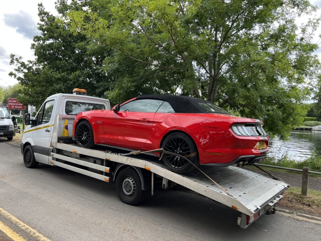 Performance car recovery Fulham: Red Ford Mustang on a Mercedes flatbed tow truck during a professional vehicle recovery.