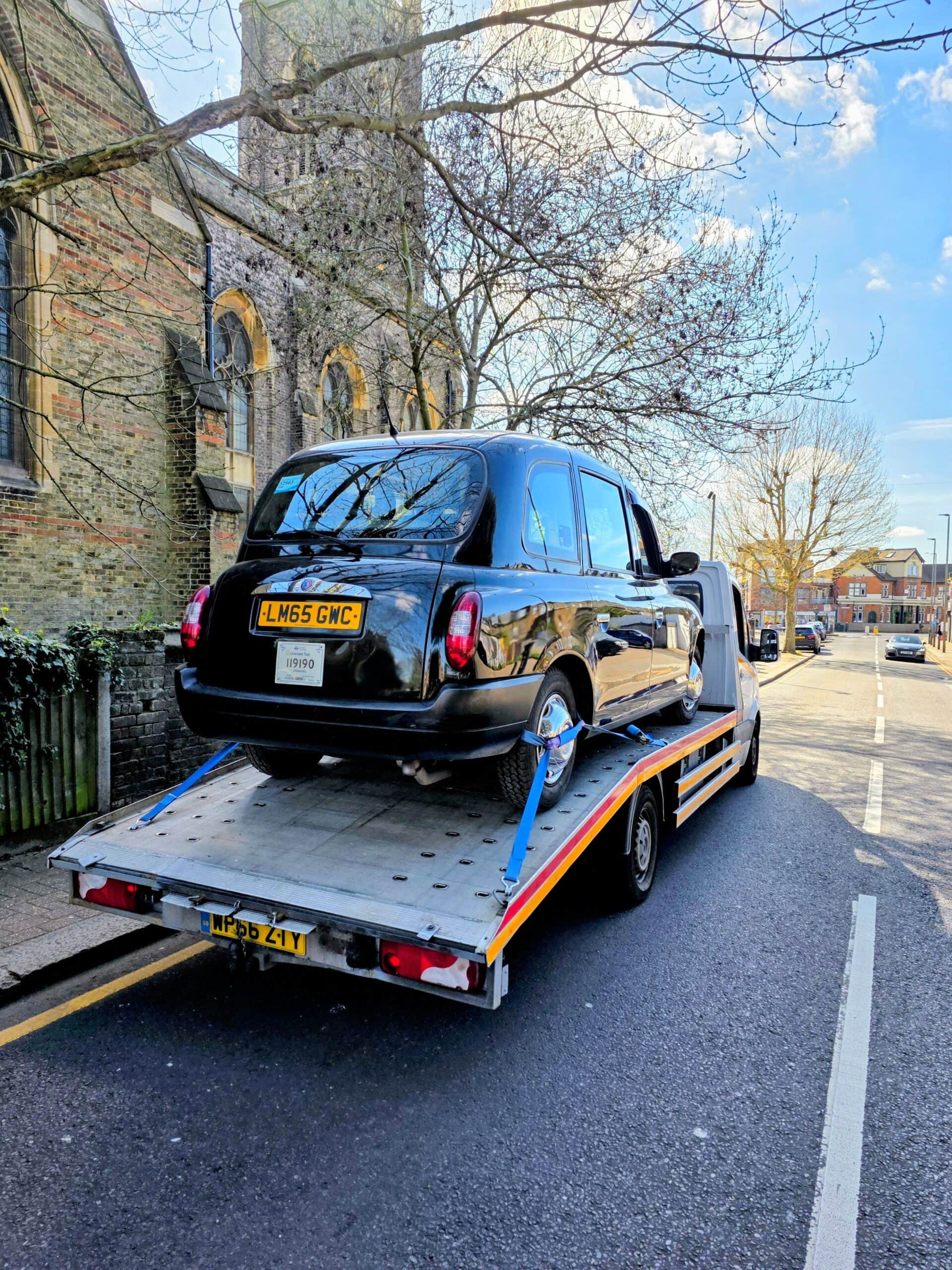 A professional flatbed recovery truck performing a specialist car recovery for a black LTI TX4 London taxi after a police impound release today.