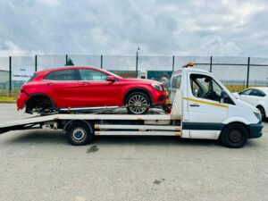 Red Mercedes-Benz GLA on a flatbed truck for professional police pound recovery and towing service in Kensington London area.