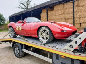 Red Ginetta G33 on a flatbed recovery truck for luxury car recovery and towing service in Kensington West London area.