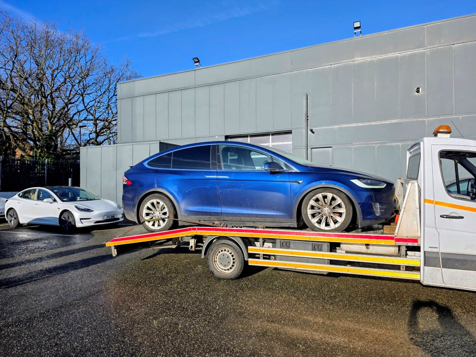 Blue Tesla Model X on a flatbed tow truck for specialist electric car recovery Wimbledon. Professional EV towing service in SW19.