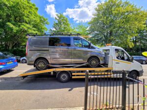 Grey Ford Transit Custom on a flatbed recovery truck for reliable van recovery Fulham service in a local SW6 residential street.