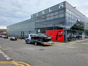 Black Tesla Model S secured on a flatbed tow truck during electric car recovery in Chiswick W4.