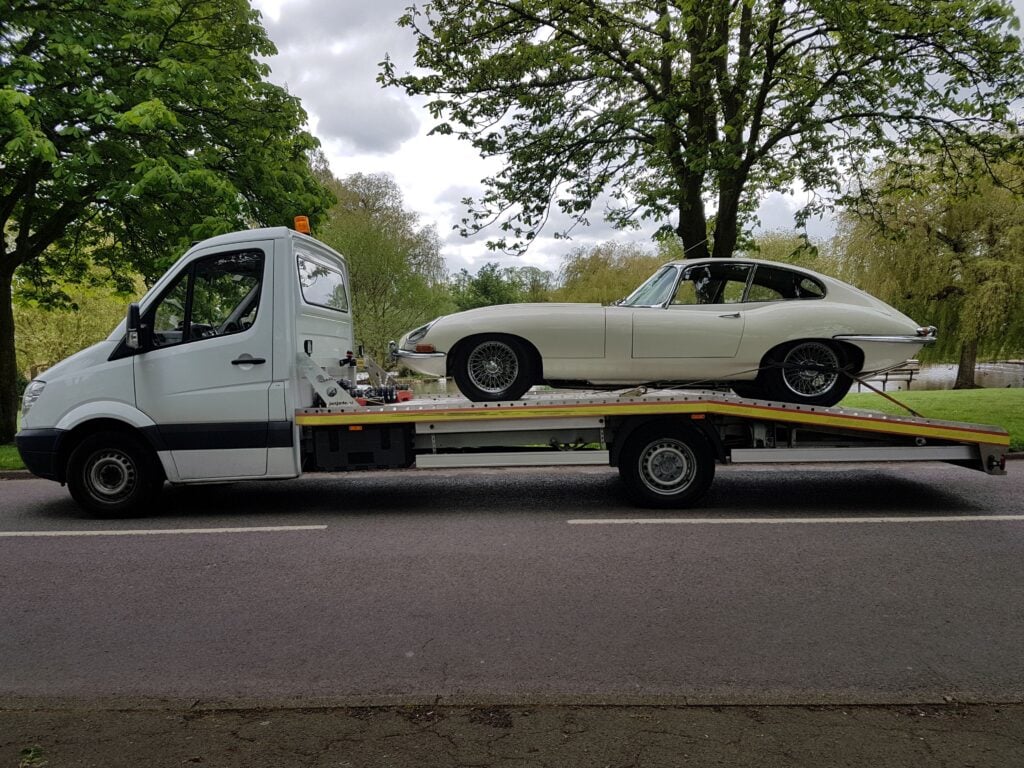 Classic Jaguar E-Type securely loaded on flatbed recovery truck — local towing company car recovery and towing service Chiswick W4